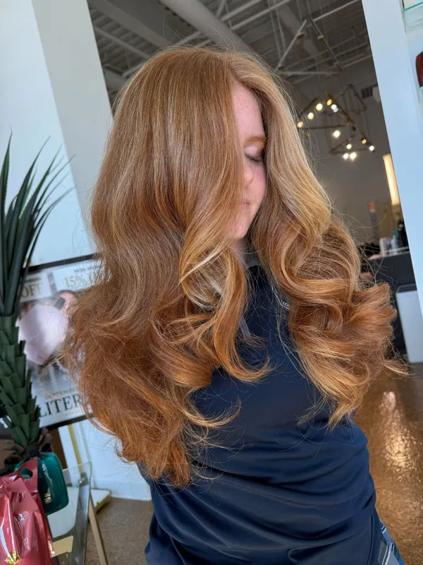 Long copper hair styled in voluminous curls by Christina White Salon